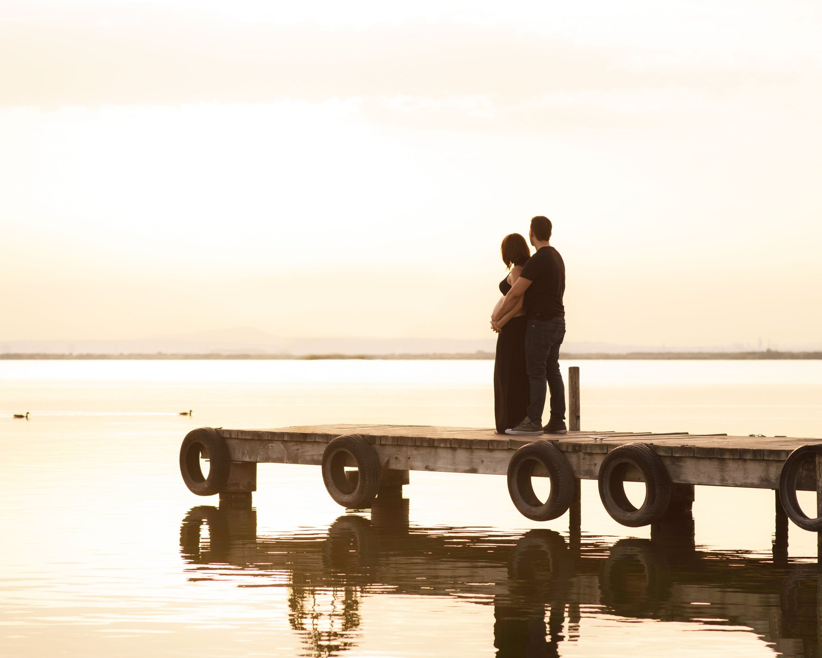 Pareja esperando a su bebé, atardecer en el embarcadero